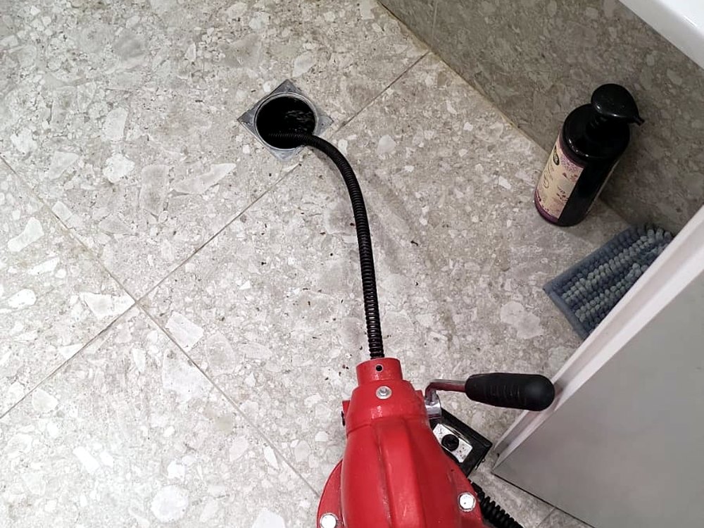 פתיחת סתימה בחדר רחצה: הכבל של הספירלה נכנס דרך פתח הניקוז שברצפה