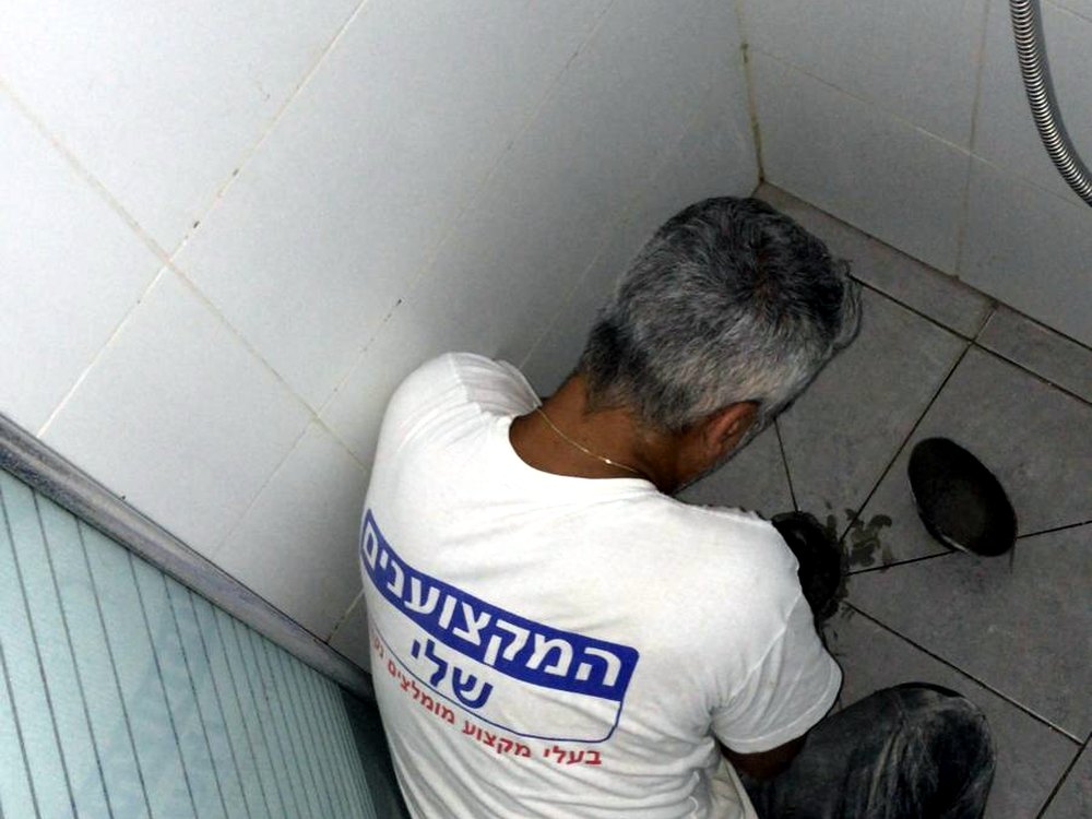 אינסטלטור של המקצוענים שלי פותח פתח ניקוז במקלחת לפני החדרת הספירלה