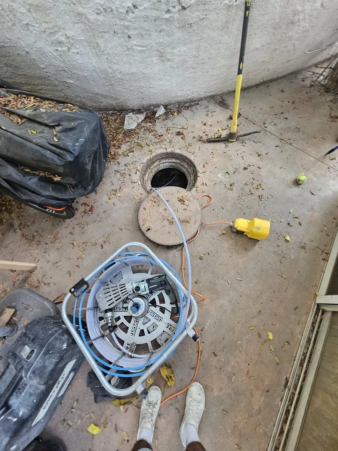 צינור מכונת הלחץ נכנס לשוחת ביוב פתוחה לשטיפת קו הביוב