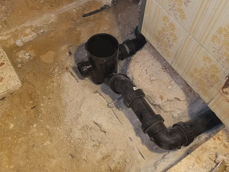 קו ביוב מפלסטיק חשוף בריצפה, עם חיבורי T וזווית — הקו שנבדק בצילום