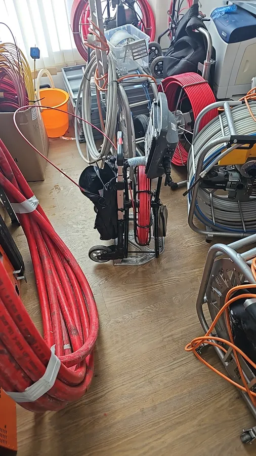 ציוד לפתיחת סתימות במחסן שלנו: מכונות ספירלה, גלילי כבל אדומים וגלילי מצלמת צנרת