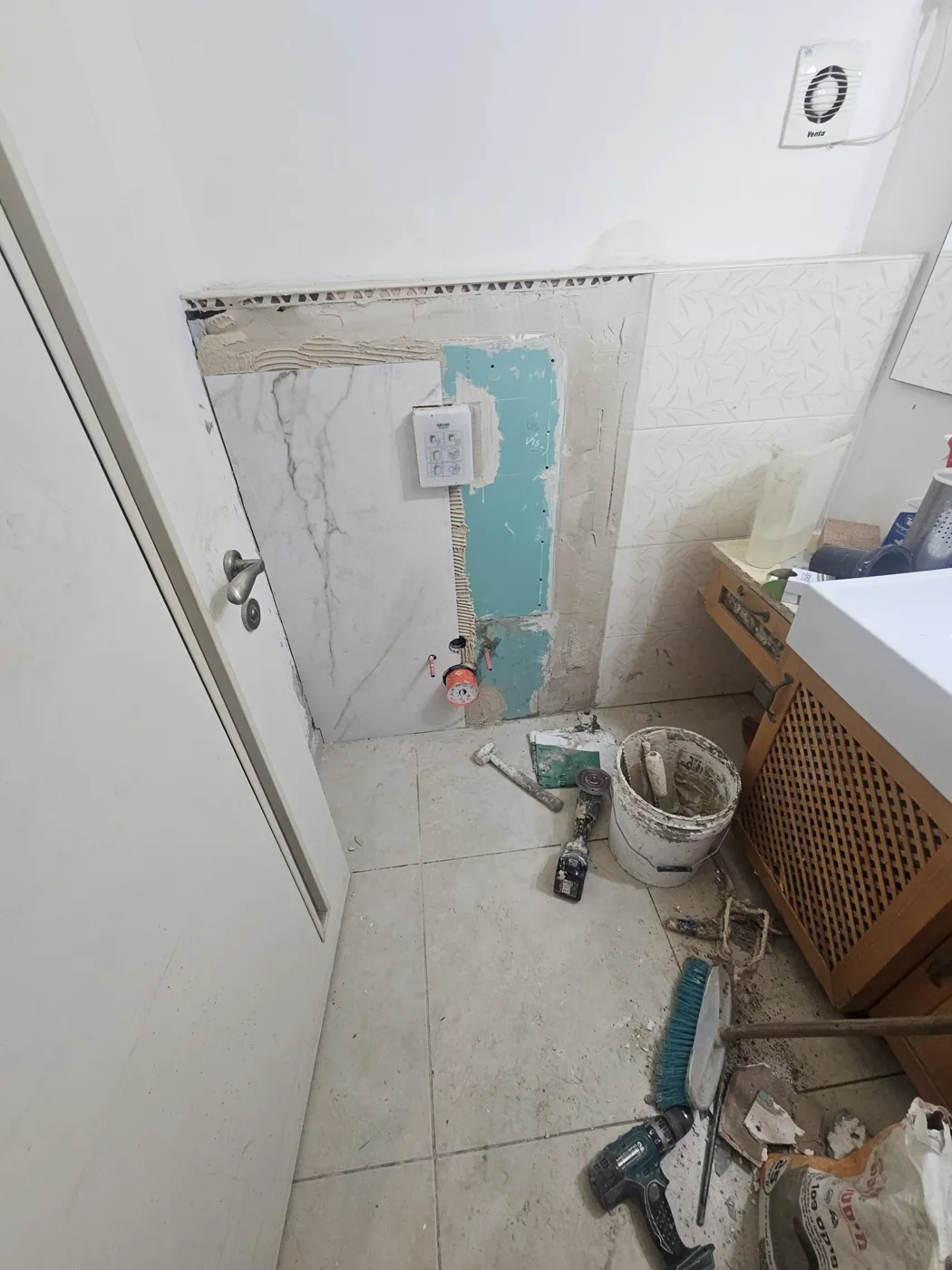 אריח ראשון על קיר הניאגרה עם פתחים לביוב ולברגי האסלה