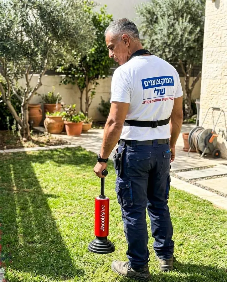 אינסטלטור סורק את הדשא עם בדיקן של גלאי גז לאורך תוואי הצנרת