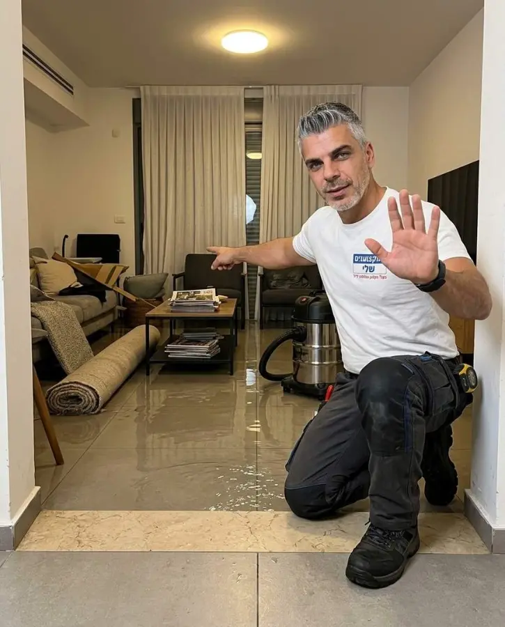 סלון מוצף מים עם שטיח מגולגל ושואב מים לפני הטיפול