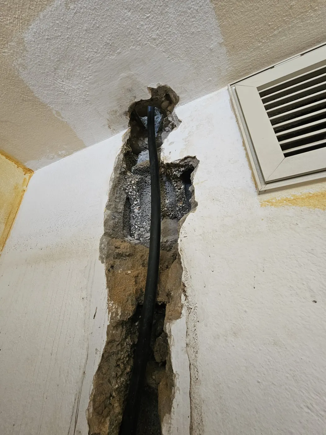צינור מים שחור חדש בתוך חריץ בקיר עד התקרה